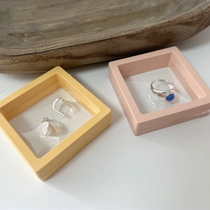 Pink and yellow PE film floating frames showing earrings and a gemstone ring