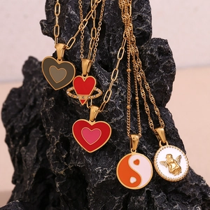 Detail of 18K gold-plated titanium steel necklaces with heart and angel pendants on rock