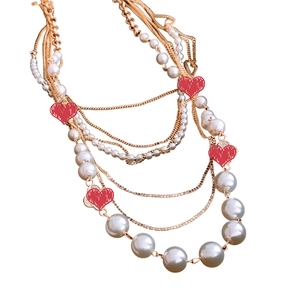 Elegant multilayer necklace with gold chains, white pearls, and red heart charms