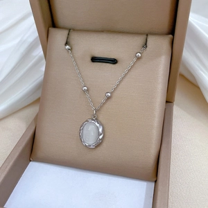 Detailed shot of titanium steel necklace with white opal pendant in a gold jewelry box