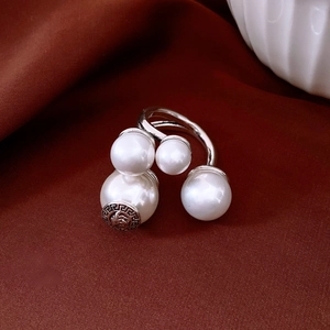 Macro shot of silver ring featuring white pearls and Greek fret pattern on dark velvet