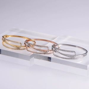 Elegant gold and silver open bangles with zircon inlay displayed on acrylic blocks