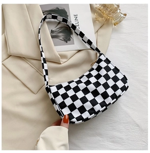 Detailed close-up of a black and white checkerboard shoulder bag with gold metal zipper