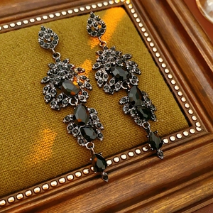 Makroaufnahme von Vintage-Ohrringen mit schwarzen Edelsteinen auf grünem Samt