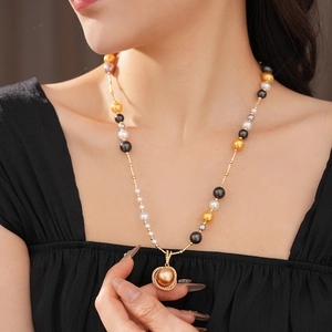 Close-up of a model wearing the pearl necklace with a large golden pearl pendant charm