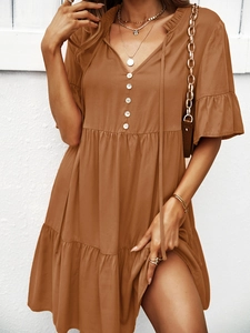 Détail d'une robe marron à col en V avec boutons décoratifs et jupe trapèze à volants