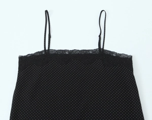 Close-up of black polka dot camisole featuring delicate white lace trim on the neckline