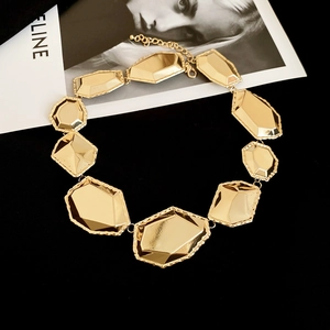 Gros plan d'un collier doré à plaques géométriques facettées avec fermoir mousqueton