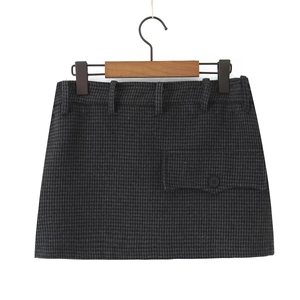 Detail of dark grey houndstooth wool skirt featuring button flap pocket and waist belt loops
