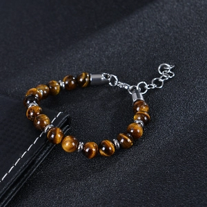 Dettaglio ravvicinato del bracciale con perle occhio di tigre e catena in argento lucido