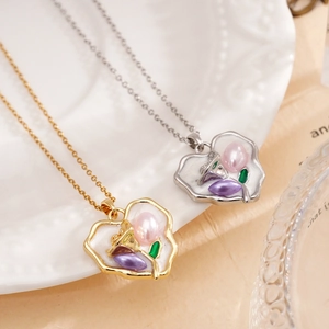 18K gold plated copper heart necklace with enamel flower pendant on a ceramic dish