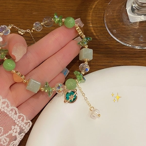 Detailed macro shot of green bead bracelet with sparkling planet pendant and gold accents