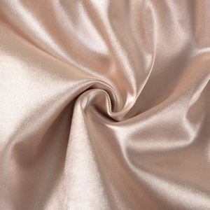 Macro shot of smooth champagne satin fabric with silk texture and elegant spiral folds