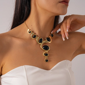Détail d'un collier pendentif ovale doré vintage avec pierres noires sur modèle