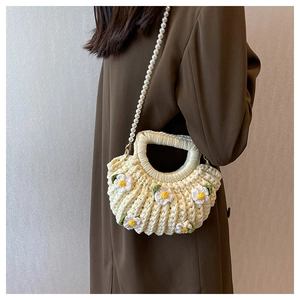 Detail of handmade cream woven bag with floral accents and elegant pearl strap