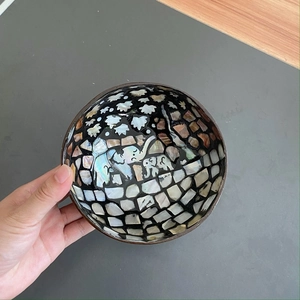 Detailed view of handmade coconut bowl with inlaid shell elephant pattern and brown exterior