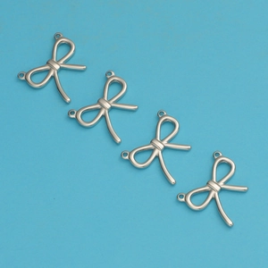 Close-up of four silver metal bow charms with double loops for DIY jewelry making