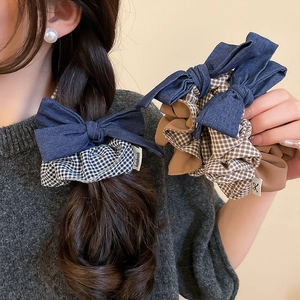 Detail of handmade fabric plaid bow scrunchie with soft denim and checkered texture
