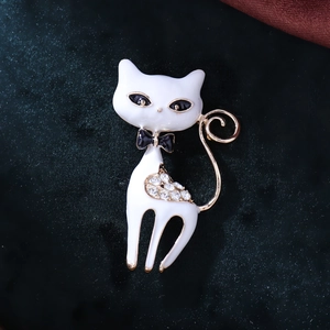Detail of cute cat brooch with white enamel finish and sparkling rhinestones on blue velvet