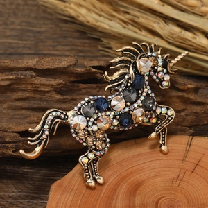 Vintage unicorn alloy brooch with blue and champagne crystals on wood surface