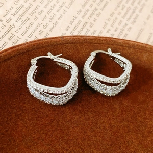 Detail of silver geometric square hoop earrings with layered zircon pavé on a velvet tray