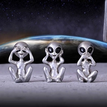 Detailed view of three silver alien figurines posing in See Hear Speak No Evil styles