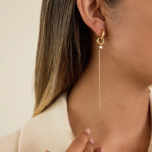 Boucles d'oreilles pendantes dorées avec pendentif zircon rond sur modèle
