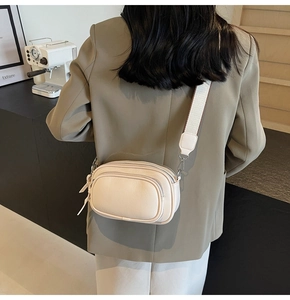 Detail showing the cream white leather crossbody bag with adjustable wide shoulder strap