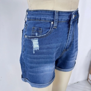 Détail du short en jean à taille haute avec texture déchirée et revers sur les jambes