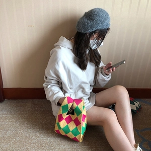 Casual lifestyle scene showing a colorful argyle knit tote bag next to a female model