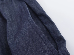Macro shot of side pocket stitching and dark blue denim texture on casual trousers