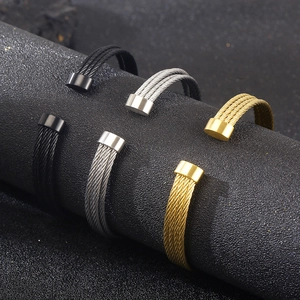 Macro detail of multi-layered stainless steel cable bracelets in gold, silver and black