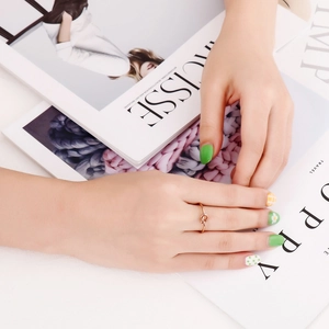 Close-up of rose gold minimalist knot ring worn by hand model over magazines
