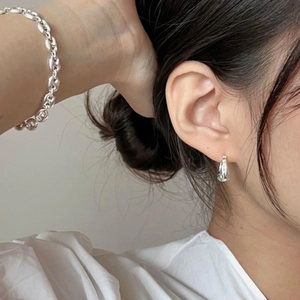 Detail of minimalist 925 sterling silver ear studs and coffee bean chain bracelet on model