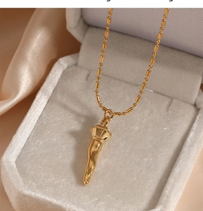 Macro shot of gold cornicello horn necklace inside a white velvet jewelry box on silk