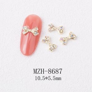 Macro view of 3D gold bow alloy nail charm with rhinestones measuring 10.5x5.5mm
