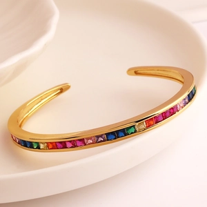 Detailopname van de gouden C-vormige armband met kleurrijke micro-gezette zirkonia-stenen