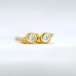 Macro shot of gold-plated geometric round stud earrings with shimmering clear zircon pavé
