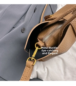Close-up of golden metal buckle and zipper detail on brown pebbled leather tote bag