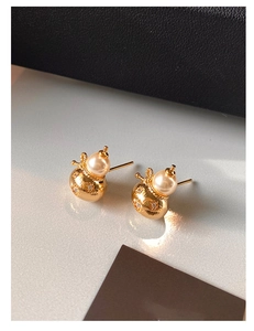 Vue macro de boucles d'oreilles gourde dorées avec perles et diamants étoilés brillants