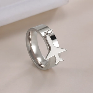 Macro detail of silver stainless steel ring featuring a hanging airplane pendant charm
