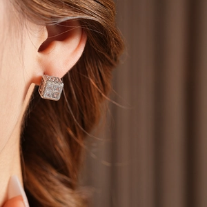 Gros plan d'une boucle d'oreille carrée argentée sertie de zircons sur un mannequin