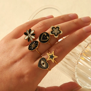 Close-up of bohemian 18k gold plated stainless steel rings with enamel daisy and heart details