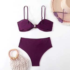 Flat lay of purple bikini with metal ring detail, sun hat and sunglasses on white background