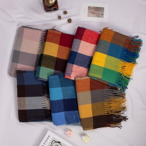 Flat lay of multiple plaid cashmere scarves with long tassels in various color patterns
