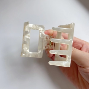 Macro detail of large square cream acetate hair claw clip with pearlescent marble texture