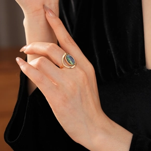 Detail of vintage gold oval ring with iridescent shell stone worn on black velvet
