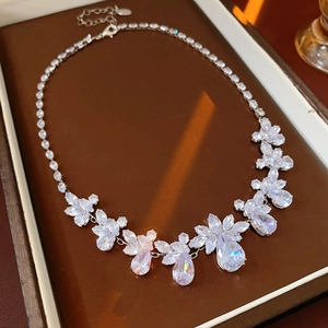 Detailed close-up of water drop and flower crystal necklace in a brown luxury jewelry box