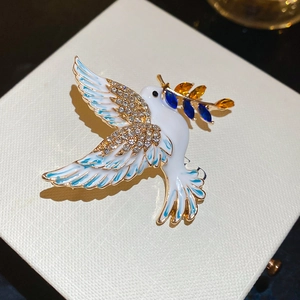 Macro detail of peace dove brooch with white enamel wings and sparkling rhinestones