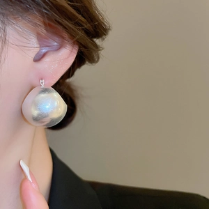 Macro detail of large silver iridescent sphere earrings with pearlescent laser finish
